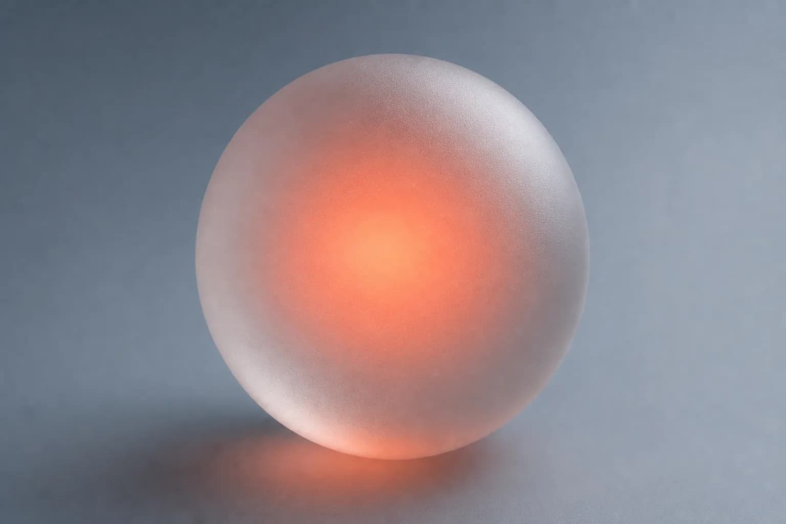 A frosted glass sphere glowing with a warm coral core
